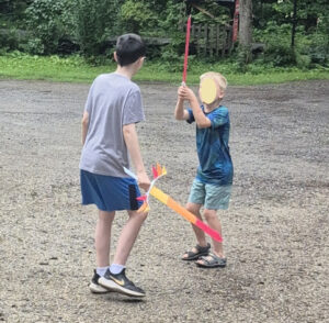 Older child guiding a younger child during cooperative outdoor play activities

